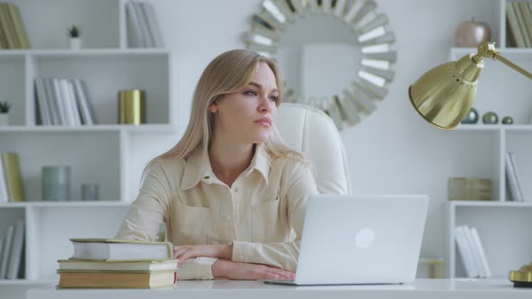 Thinking woman with laptop at the desk at home office