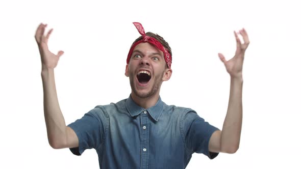 Successful Young Bearded Man with Red Bandana Shouting for Joy Celebrating Victory Winning or