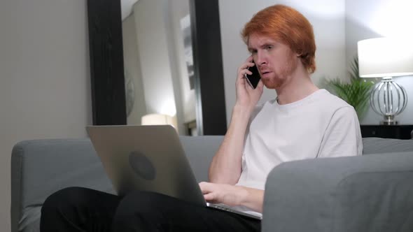 Redhead Man Talking on Phone While Working on Laptop