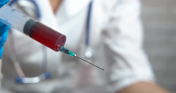 Medical worker with blood syringe. 