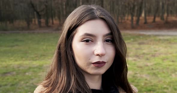 Portrait of Young Attractive Female Looking at the Sliding Camera on Autumn Park. Cheerfully Pretty