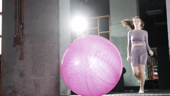 Young Woman Doing Pilates  Running to the Fitness Ball and Sits Down on It