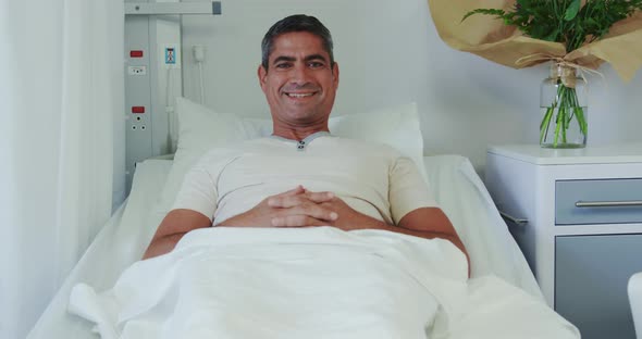 Front view of Caucasian male patient relaxing on hospital bed in hospital ward 4k