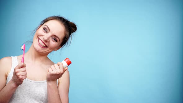 Woman Holds Toothbrush and Paste