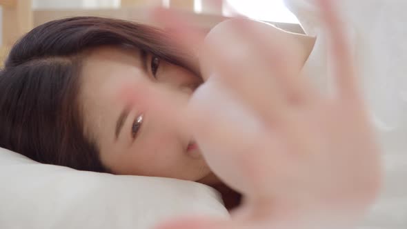 Asian woman smiling lying on bed in bedroom, Beautiful japanese using relax time after wake up.