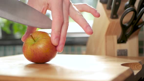 Slow motion shot of an apple being cut in half with a sharp knife.