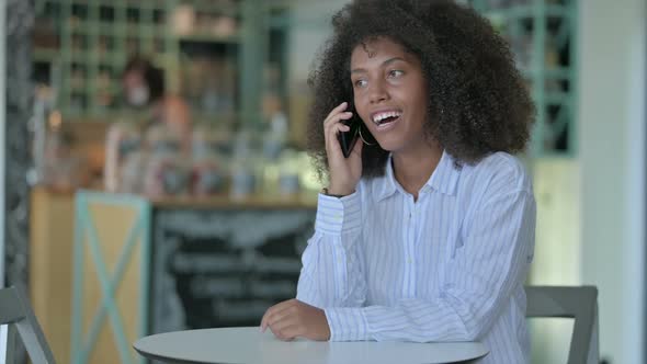 Cheerful African Businesswoman Talking on Smartphone in Cafe