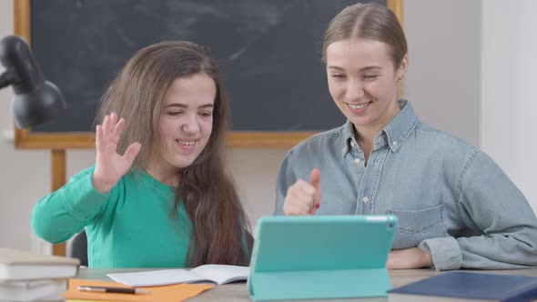 Positive Caucasian Young Woman and Little Person Waving at Tablet Video Chat Smiling Sitting in