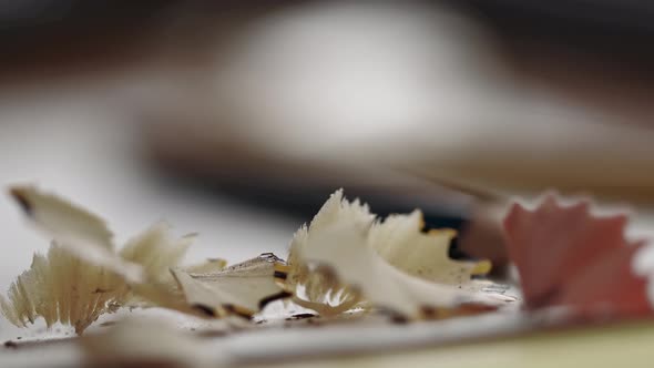 Close-up of shavings from a pencil falling on the table. Sharpening a pencil.