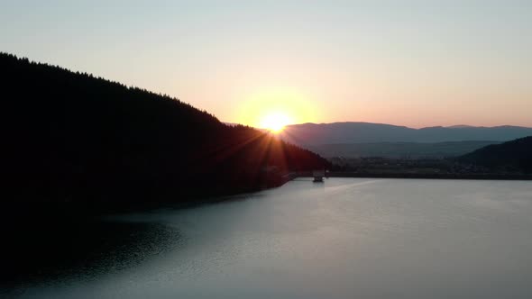 Golden Sunset Setting Behind Mountains In Frumoasa Dam, Romania. - aerial reveal