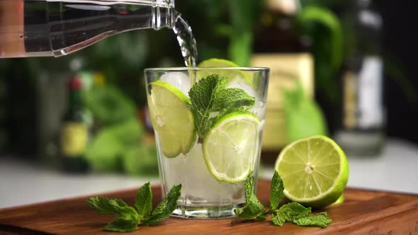 Slow Motion Mineral Water or Soda Fill Glass with Lime, Mint and Ice Cubes. Food Background.