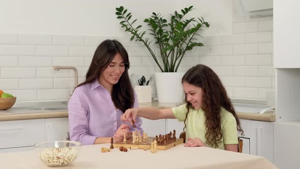 Cheerful Daughter Wins Mom in Chess and Rejoices While Sitting at the Table at Home