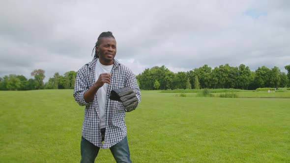 Active Handsome African Man Catching Ball in Baseball Glove Outdoors