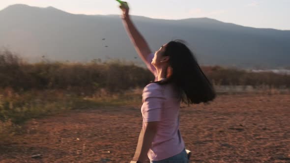 Beautiful asian woman blowing soap bubbles in the summer park at sunset.