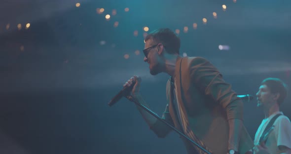 Side View Portrait of a Man Singing to Microphone on Light Background