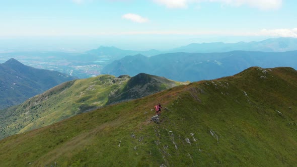 Aerial: couple backpackers hiking on mountain top Summer adventures on the Alps