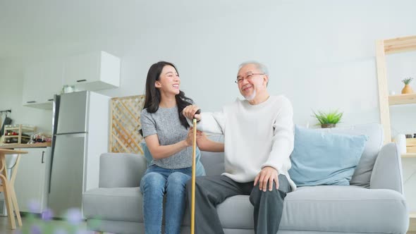 Asian young daughter support senior older man walk with walker at home.