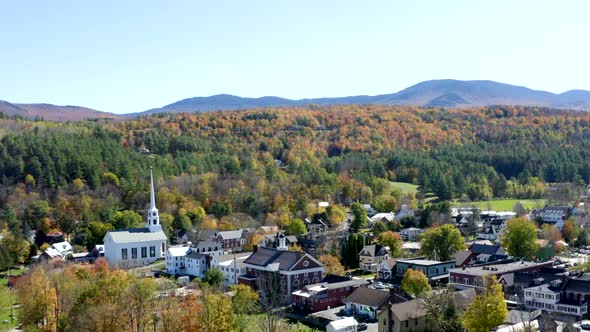 Aerial Drone Fight over a New England Town during the Fall Foliage Season Featuring a White Church a