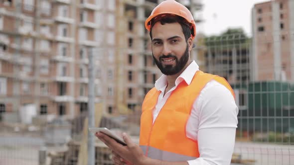 Portrait of Construction Worker on Building Site with Tablet Looking at the Camera