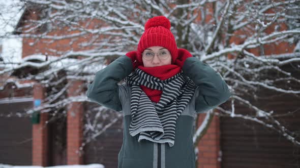 Young woman wraps herself in a scarf in the cold, glasses for vision fog up