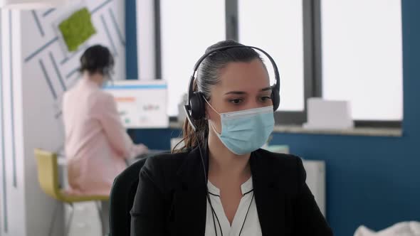 Close Up of Executive Manager with Face Mask and Headset Working on Laptop Computer