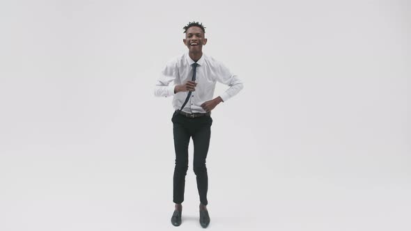 African-American man in office suit happily and emotionally dances on white background, front view.