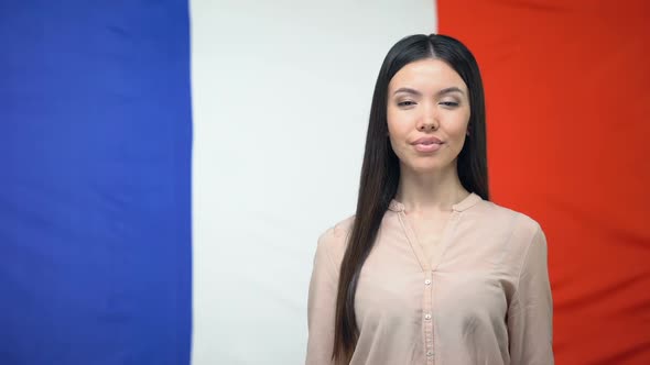 Smiling Woman Holding Passport Against French Flag Background, Travel Abroad