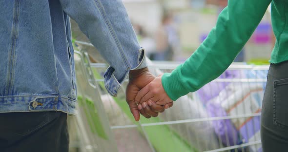 Cropped Shot of Multiethnic Couple Holding Hands in Supermarket