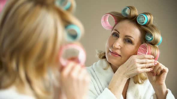 Beautiful Aged Lady Putting Hair Curler and Smiling Into Mirror, Beauty Tricks