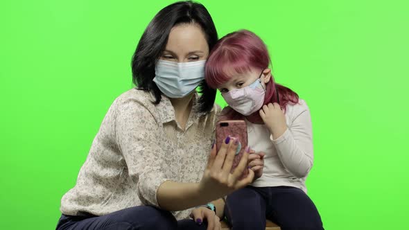 Mother, Daughter Wearing Medical Mask Holding Smart Phone Talking on Video Call