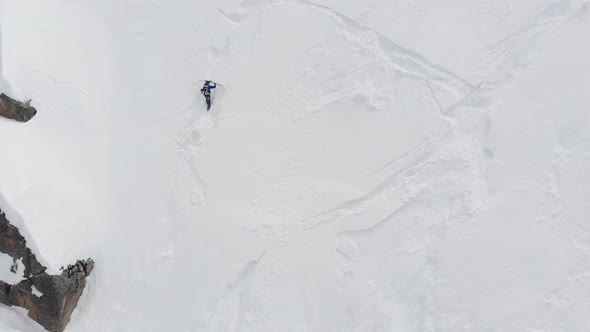 An Aerial View of a Male Athlete Athlete Skier Clambering Up a Steep Slope Up