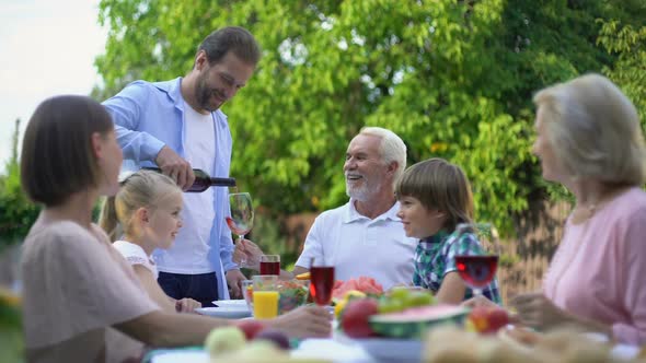 Man Pouring Expensive Aged Wine to Senior Father, Family Celebration Traditions