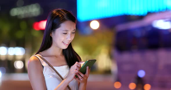 Young woman use of mobile phone in the city at night