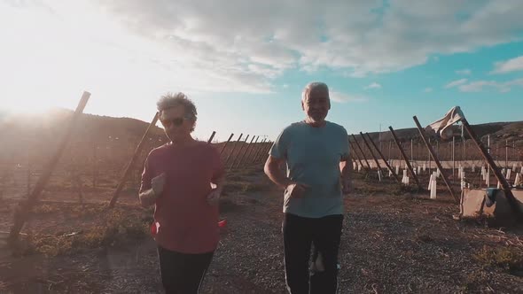 Couple of adults mature caucasian man and woman do jogging in the countryside