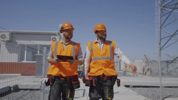 Male Engineers Walking and Talking on Power Plant