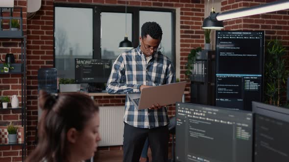 Portrait of African American Programer Standing Working on Laptop Looking Up and Smiling