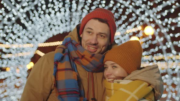 Joyous Couple Standing in Tunnel of Christmas Lights