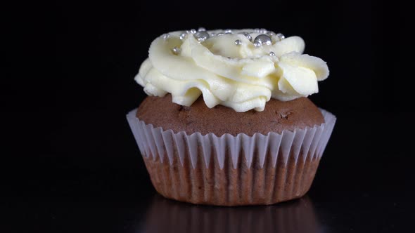 Vanilla cupcake with berry filling and honey cream cheese on black background