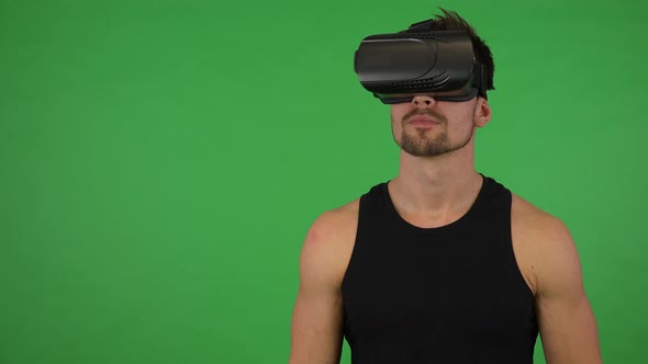 A Young Handsome Athlete Uses VR Glasses - Green Screen Studio