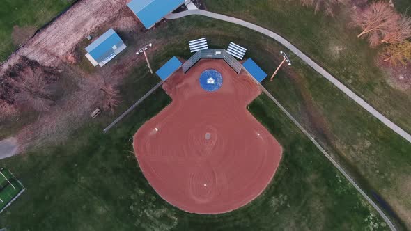 Aerial drone top backward moving shot over a green baseball and soccer fields during on a sunny even