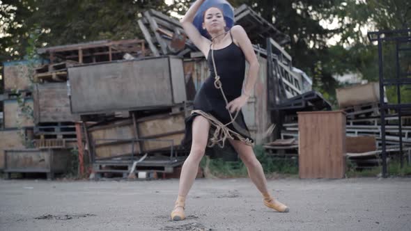 Young Caucasian Woman in Pointes Bound with Rope Dancing on Urban Slum