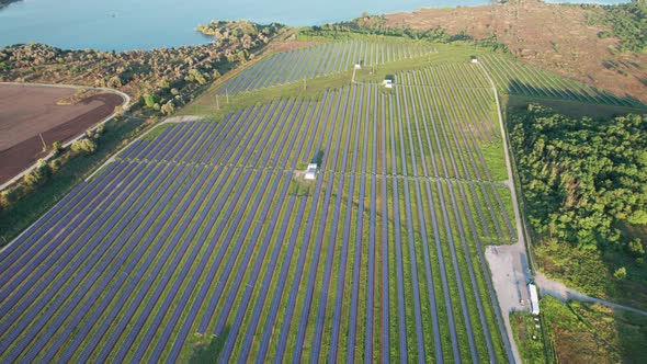 Aerial View Solar Power Station on Green Field at Sunset Solar Panels in Row