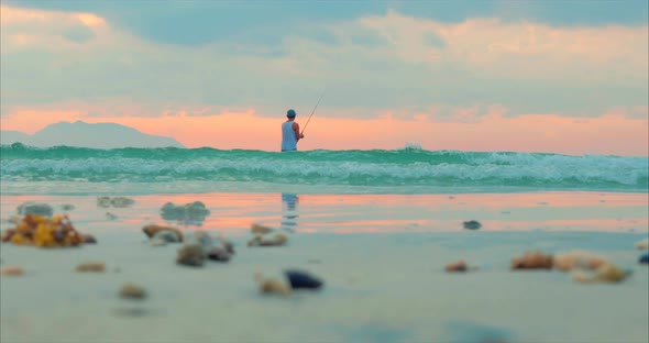 Beautiful Sunset in the Tropics on the Background of a Fisherman Who Fishes on Spinning in the Ocean