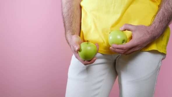 Man Holds the Apples in His Hands at the Level of the Genitals and Examines Them Turning Them in