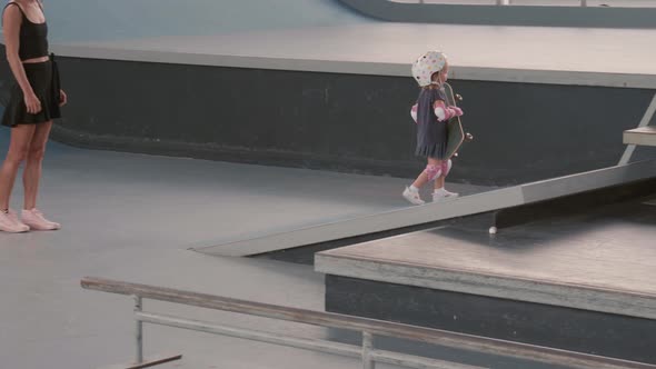 Young Mother Watching Her Kid Skateboarding