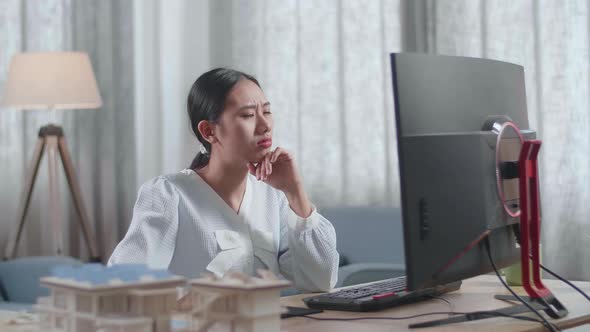 Woman Engineer With The House Model Thinking Then Raising Index Finger While Working On A Desktop