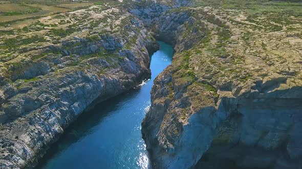 Arial shot of  Wied Il-Ghasri, a secluded inlet with a tiny pebbly beach wedged between high cliffs