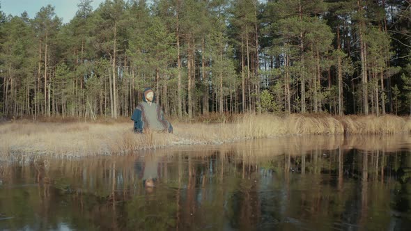 TRACKING REVERSE shot of an ice bather doing conscious breathing by a frozen lake