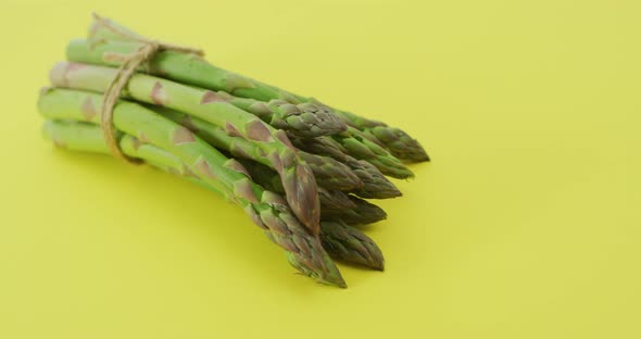 Video of close up of bundle of fresh asparagus over green background