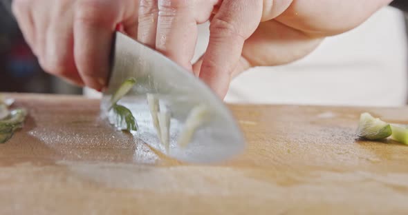 Slow motion close up of a chef knife slicing a cucumber